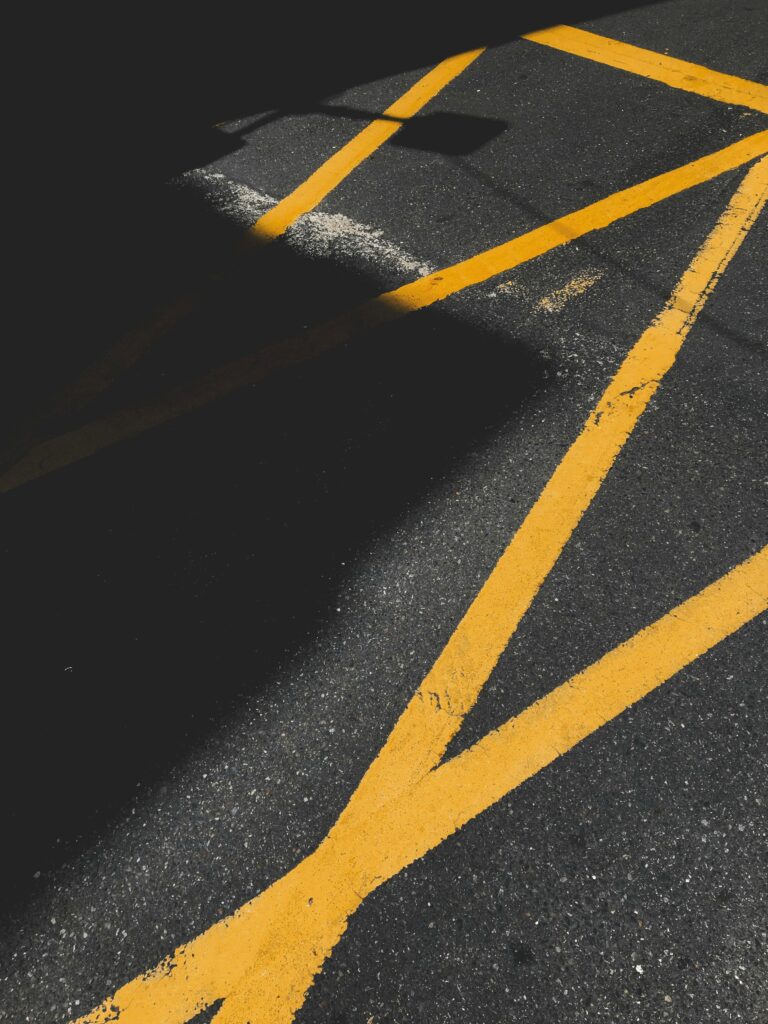 Abstract view of road markings with dramatic shadows and yellow lines.