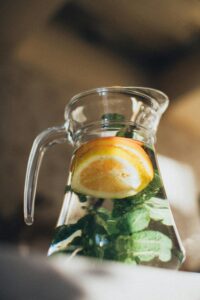A pitcher of fresh lemon water with mint leaves, captured with warm lighting.